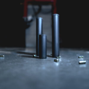 Cinematic product image of the TacSol Premium Rimfire Suppressors with bullet shells scattered around.