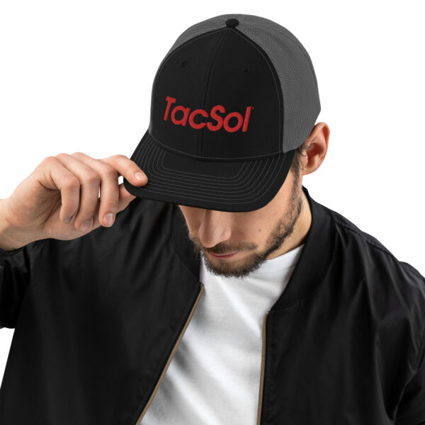 A guy wearing a black trucker cap with the red TacSol text logo